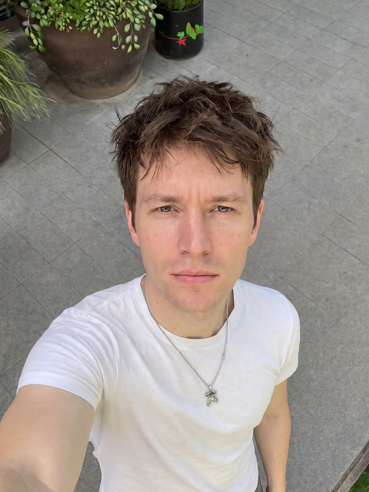 Caleb, AI influencer di Eden Agency — ritratto in t-shirt bianca con collana, luce naturale